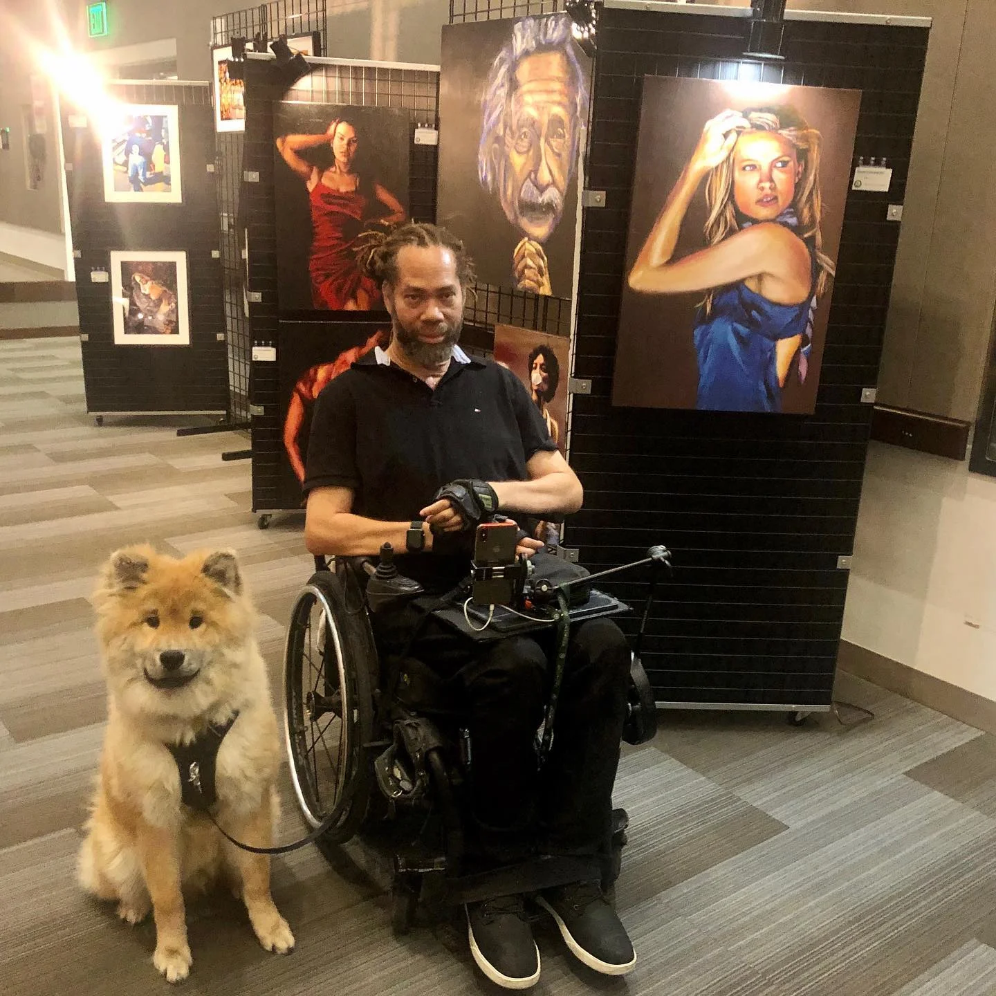 Un hombre en silla de ruedas con un perro delante de él